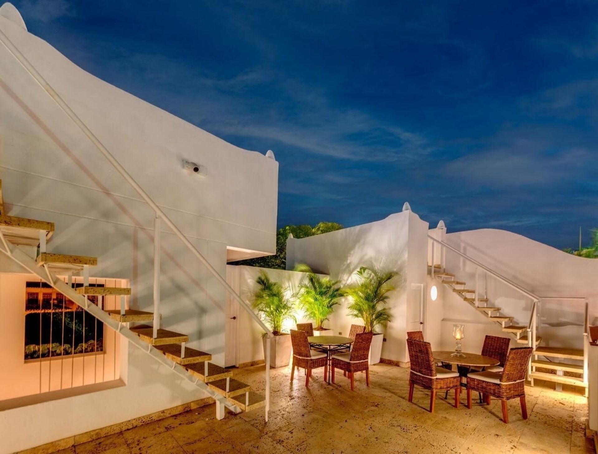 Un patio con mesas y sillas y escaleras por la noche.