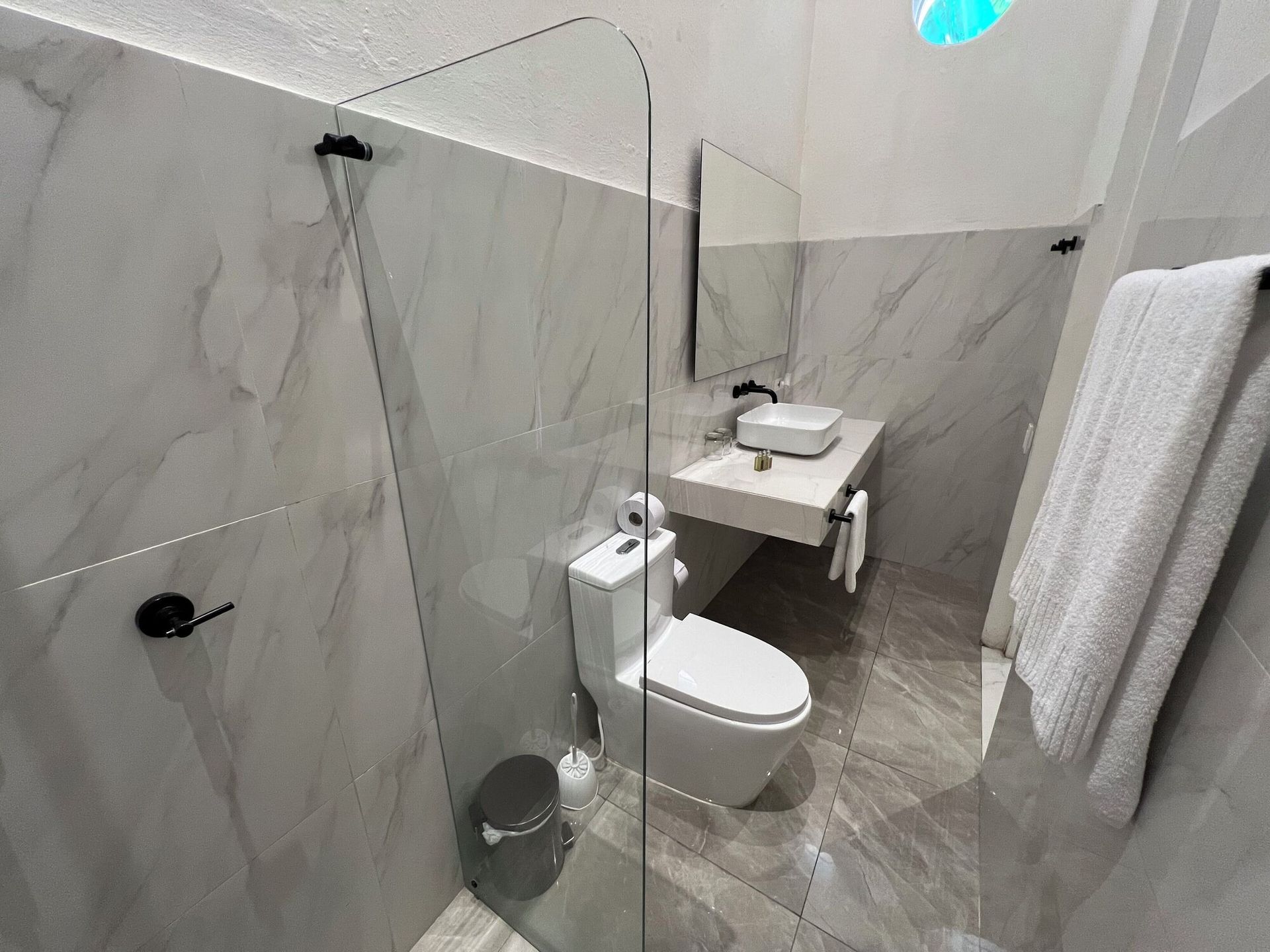 Un baño con inodoro, lavabo, espejo y ducha.