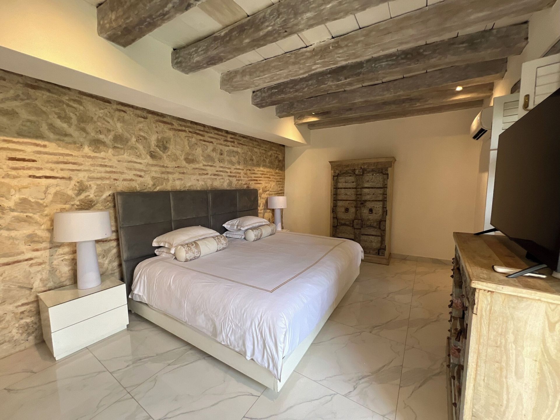 Un dormitorio con una cama grande, tocador, mesita de noche y televisión.