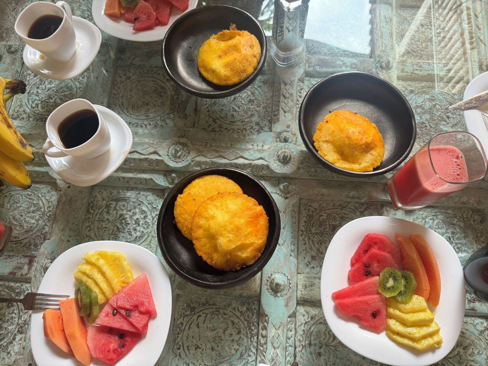 Una mesa de cristal cubierta con platos de comida y bebidas.