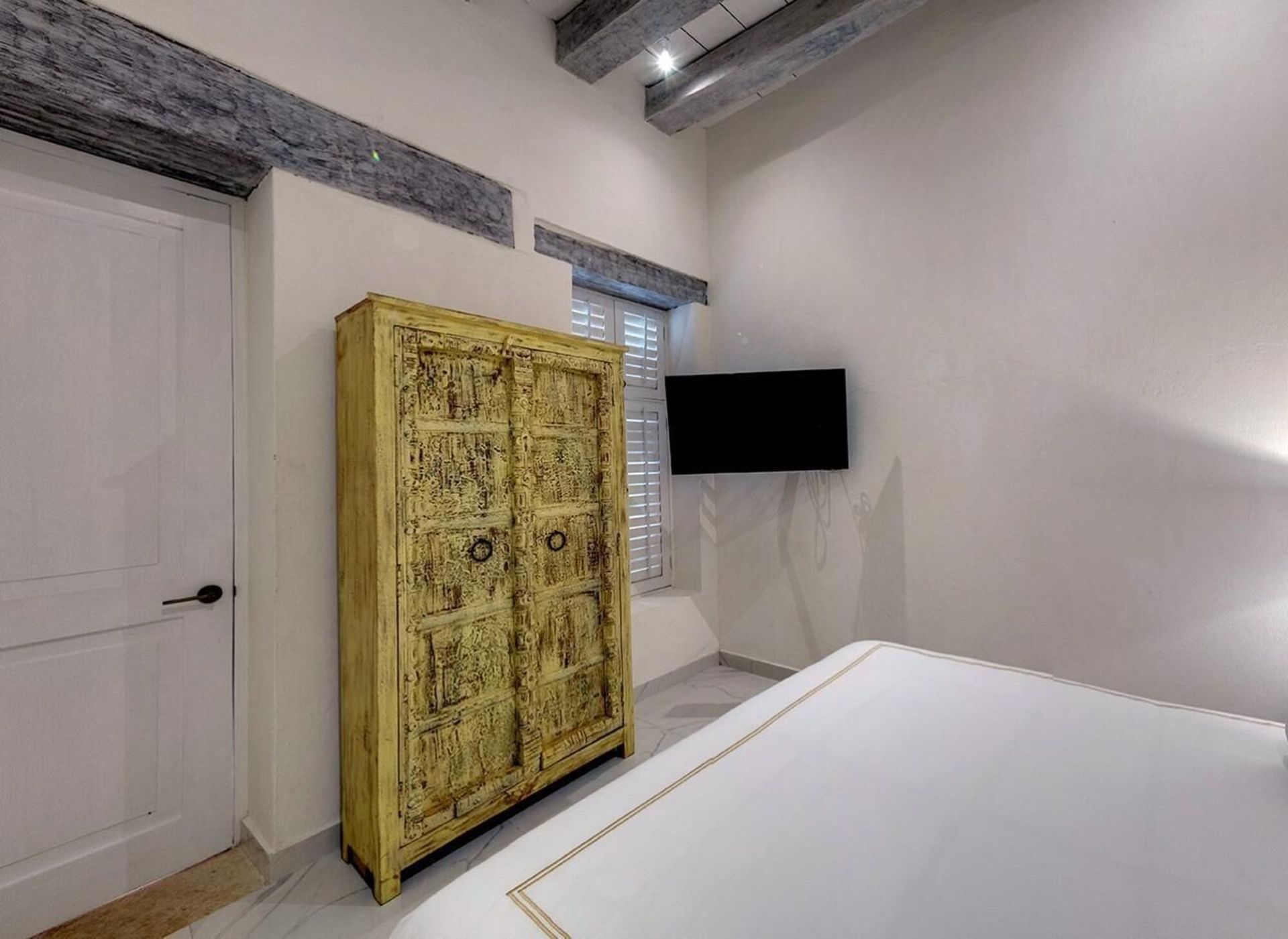 Un dormitorio con cama, tocador y televisión.