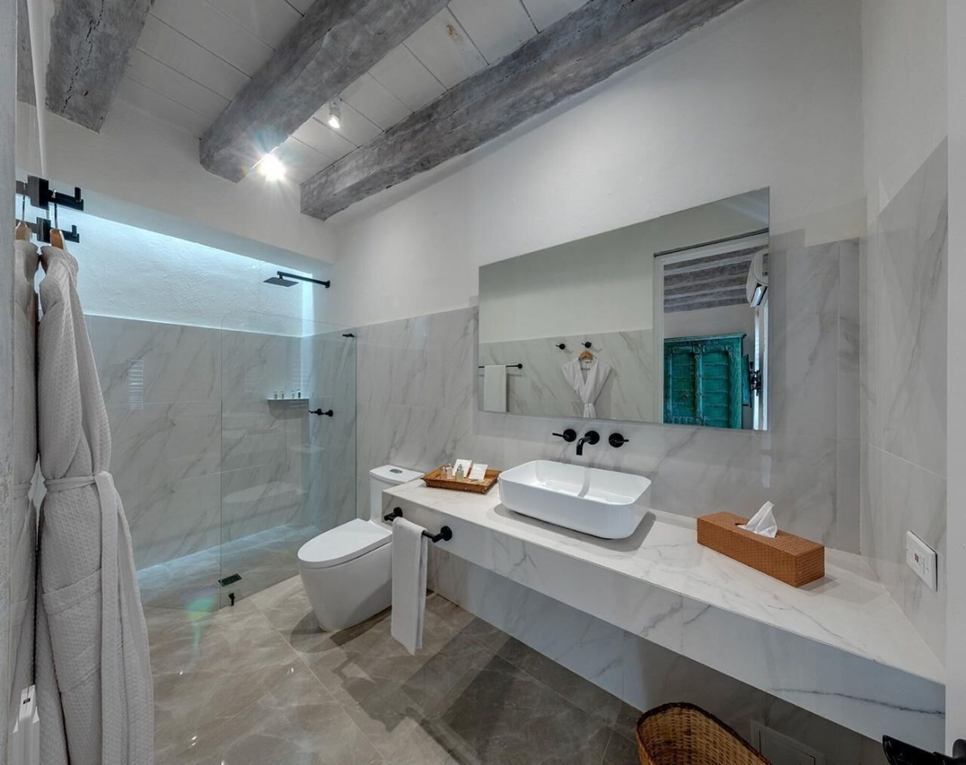 Un baño con inodoro, lavabo, espejo y ducha.