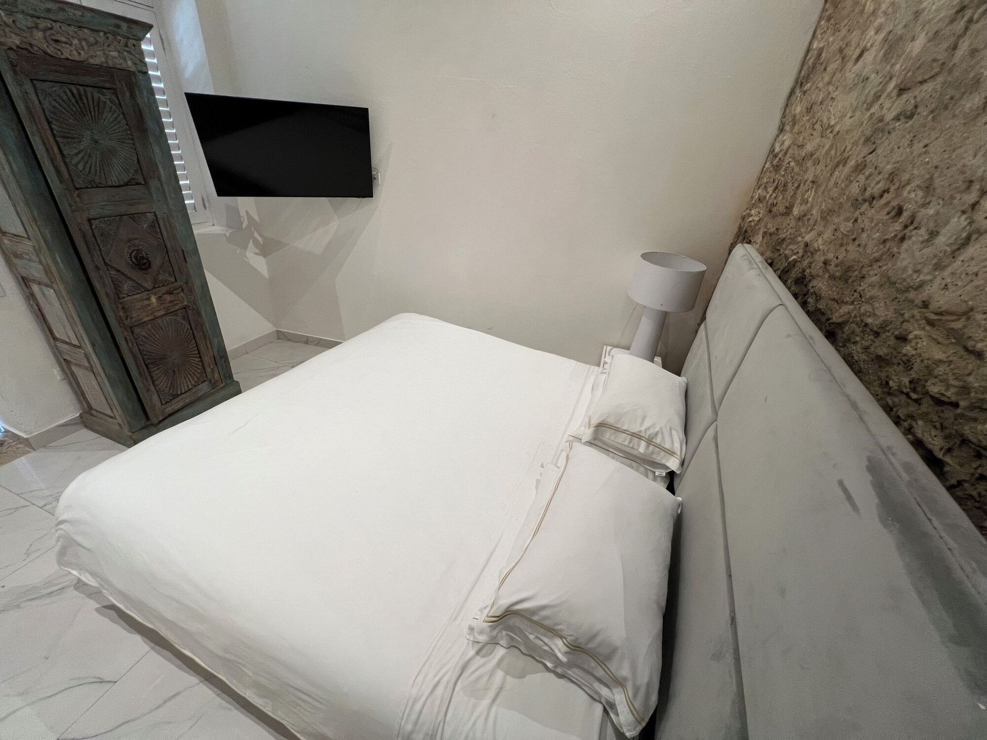 Un dormitorio con una cama y un televisor en la pared.