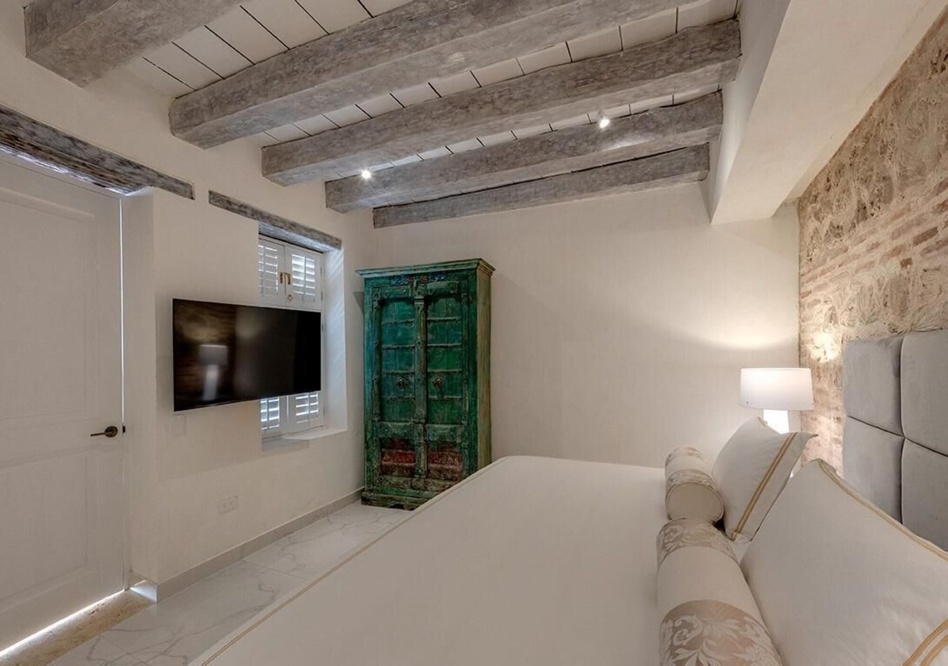 Un dormitorio con una cama, televisión y un armario verde.