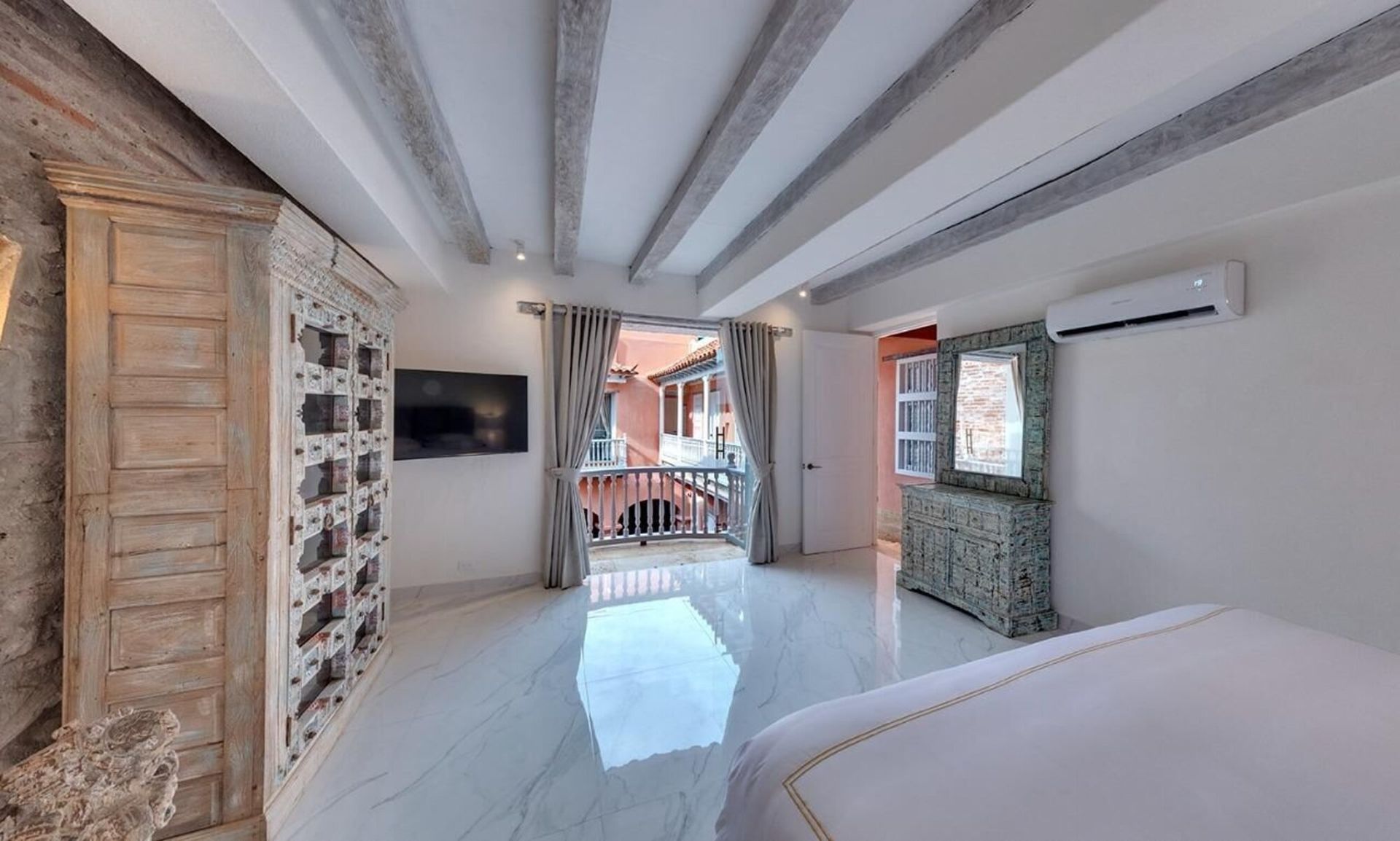 Un dormitorio con cama, televisión y balcón.