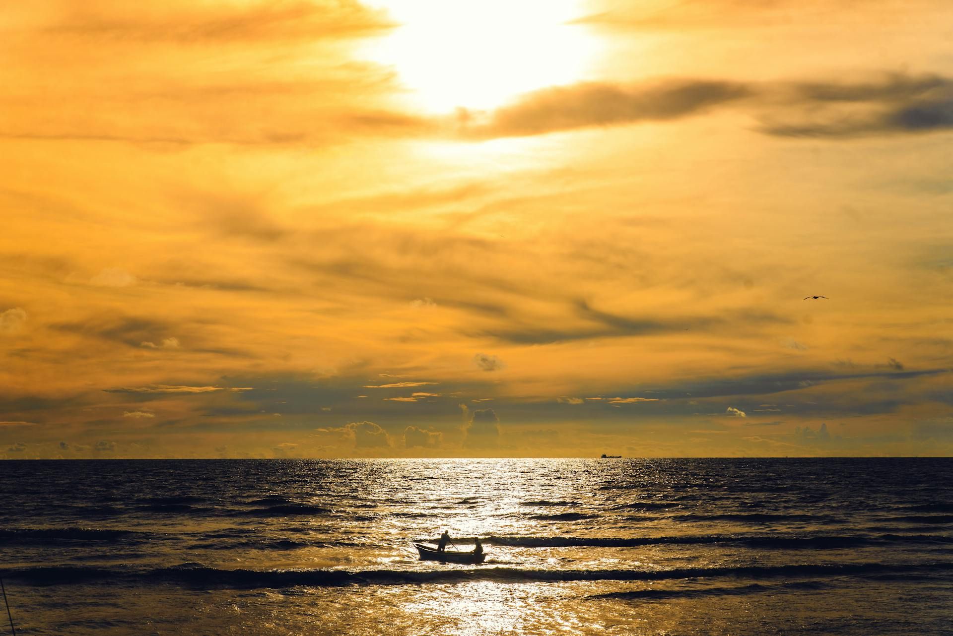 Una puesta de sol sobre el océano con un barco en el agua.