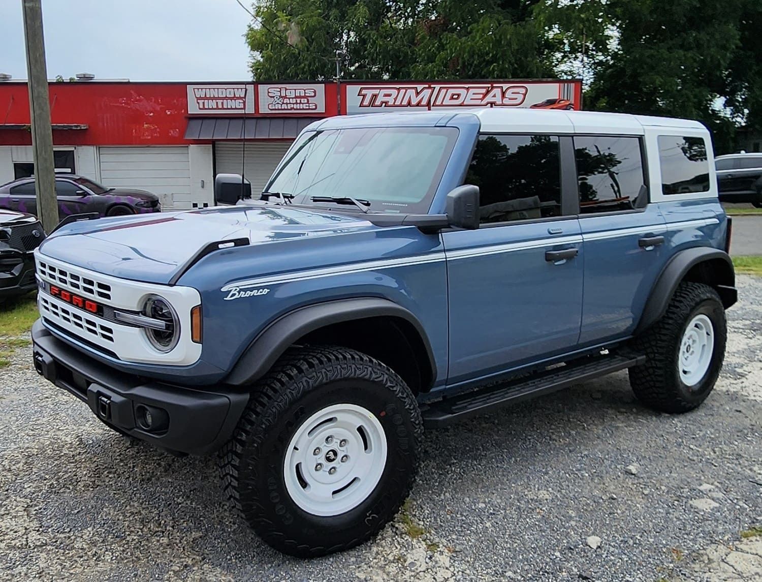 a ford bronco is parked in front of a trim ideas store