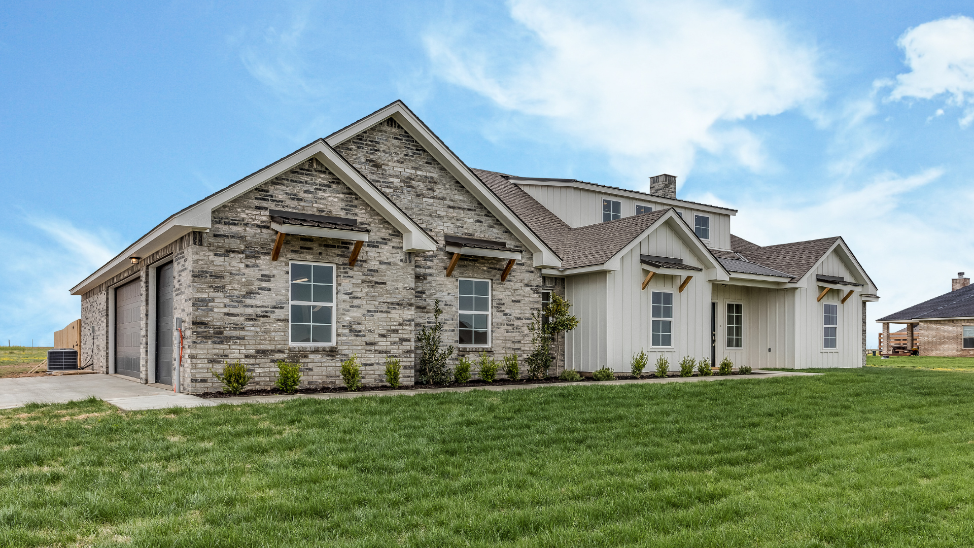 a large brick house is sitting on top of a lush green field .