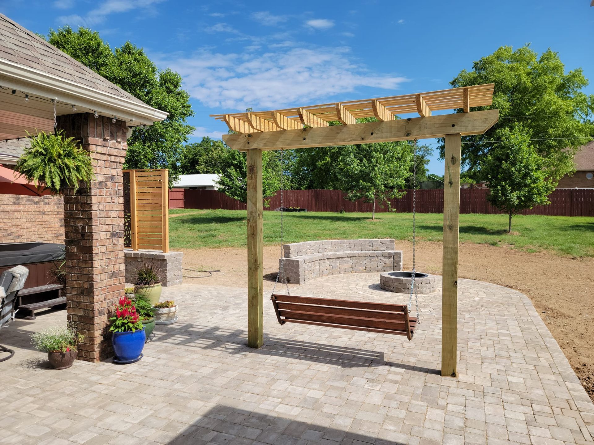 A wooden pergola is sitting on top of a patio next to a fire pit.