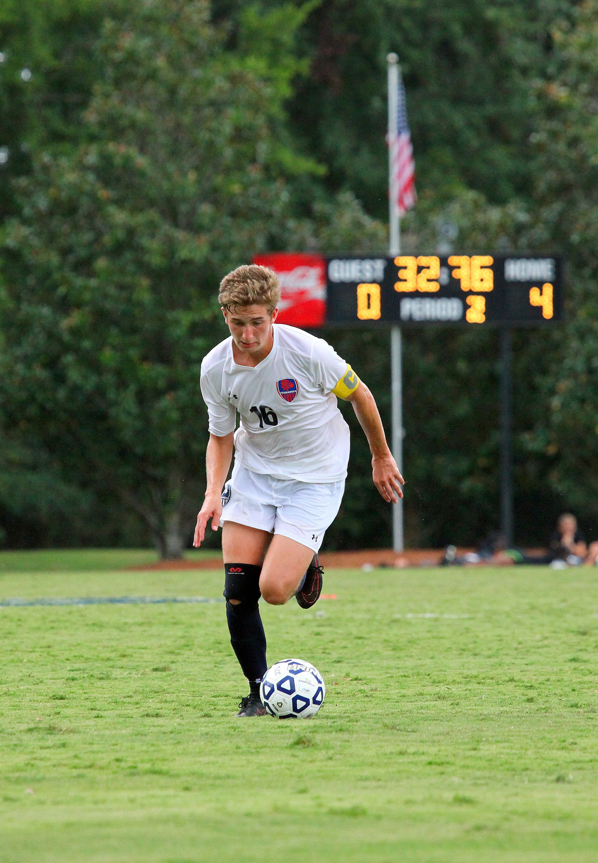 A young man is kicking a soccer ball on a field.
