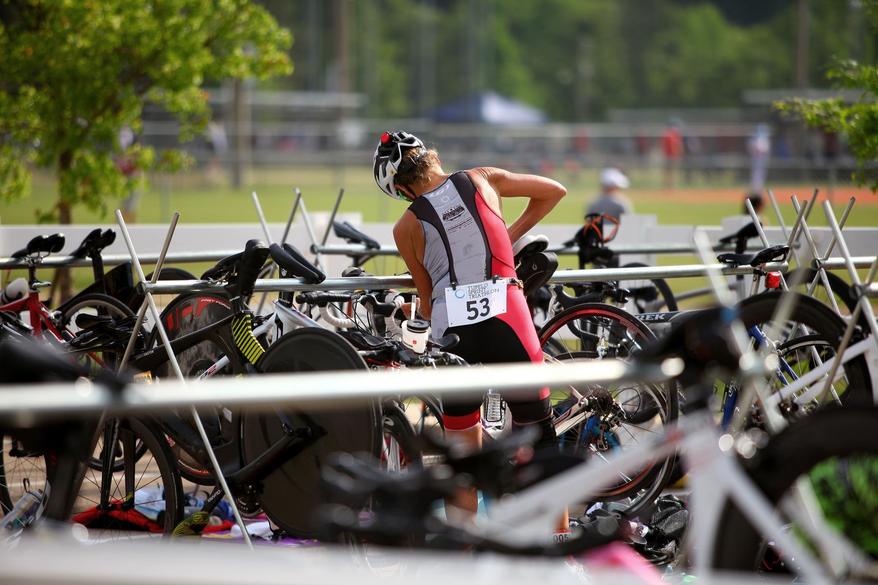 A woman triathlete is standing in front of a row of bicycles.