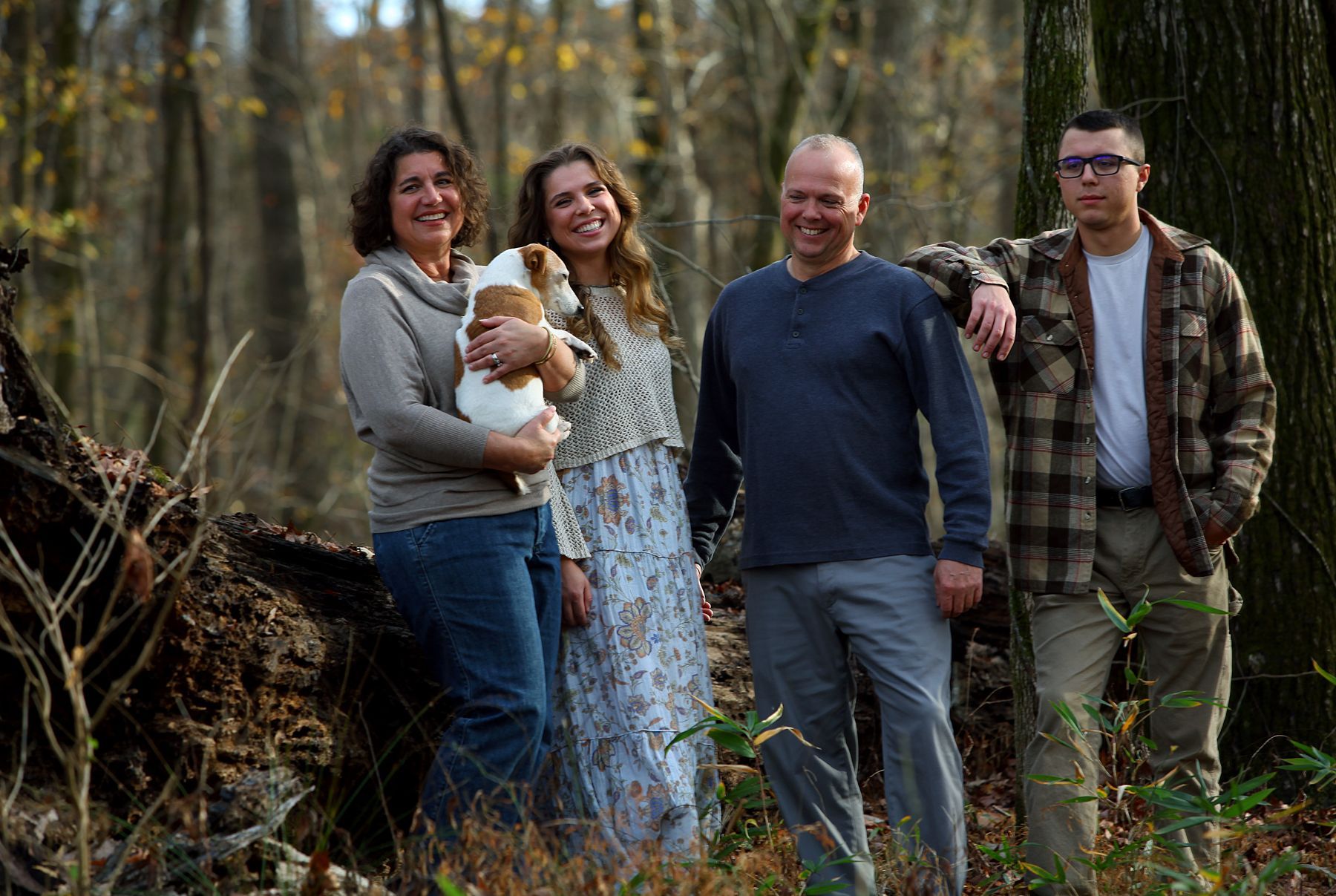A family is posing for a picture in the woods.