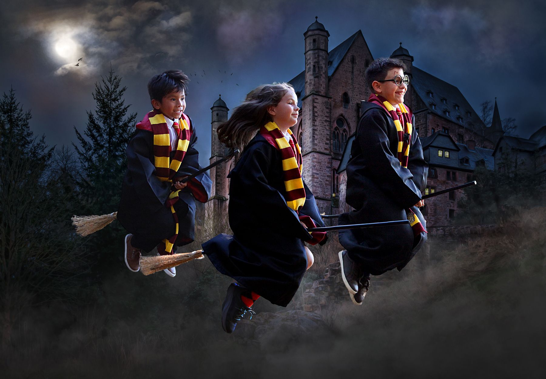 Three children are flying on brooms in front of a castle.