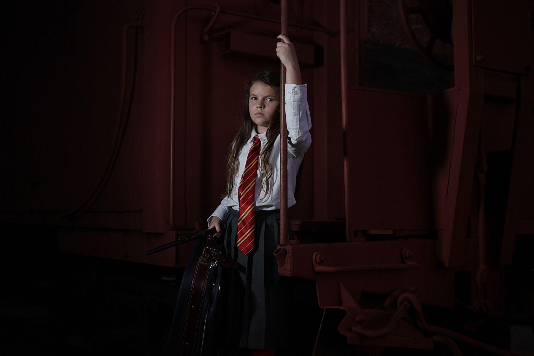 A young girl in a harry potter costume is on an old train car.