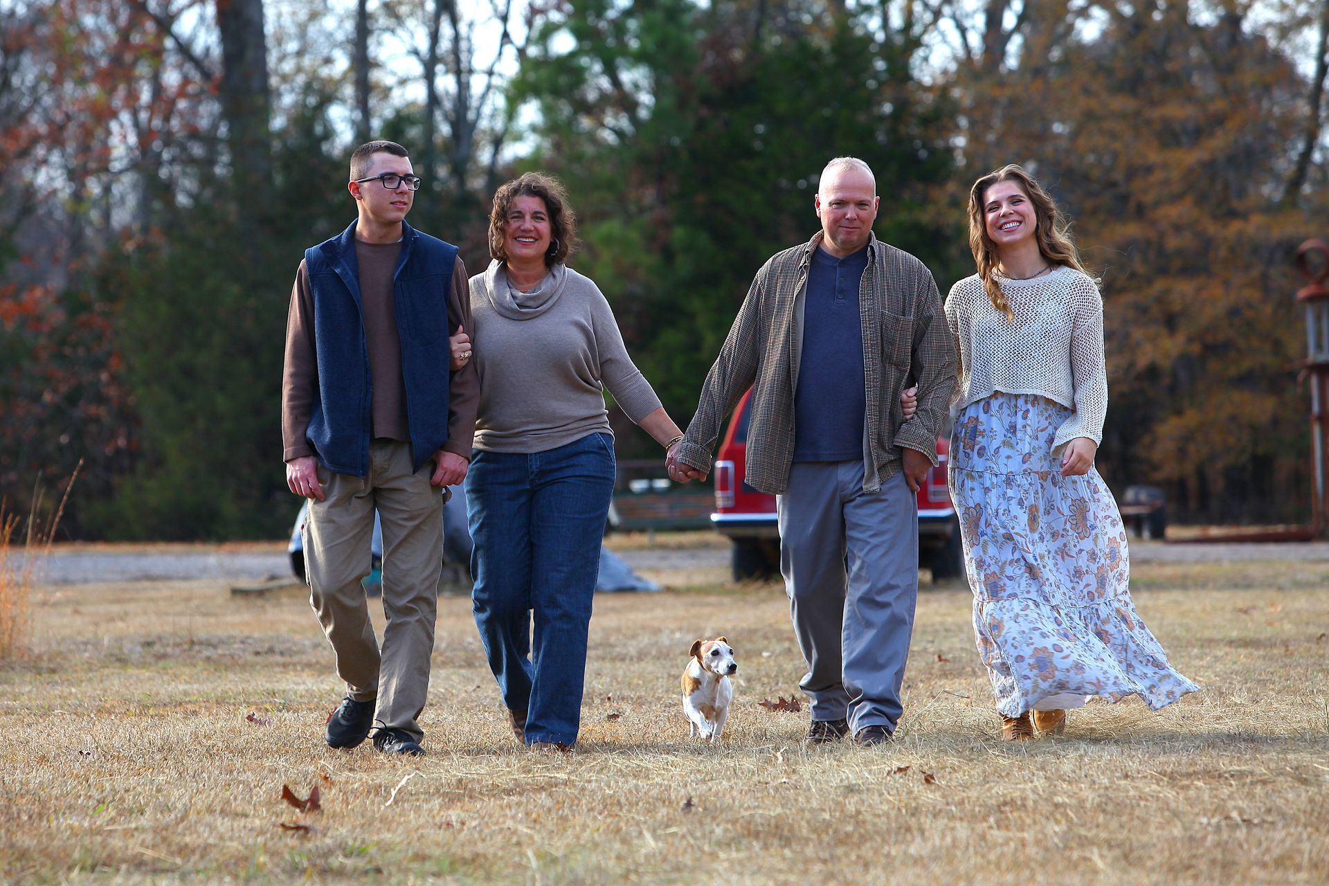 A man and a woman are walking in a field holding hands