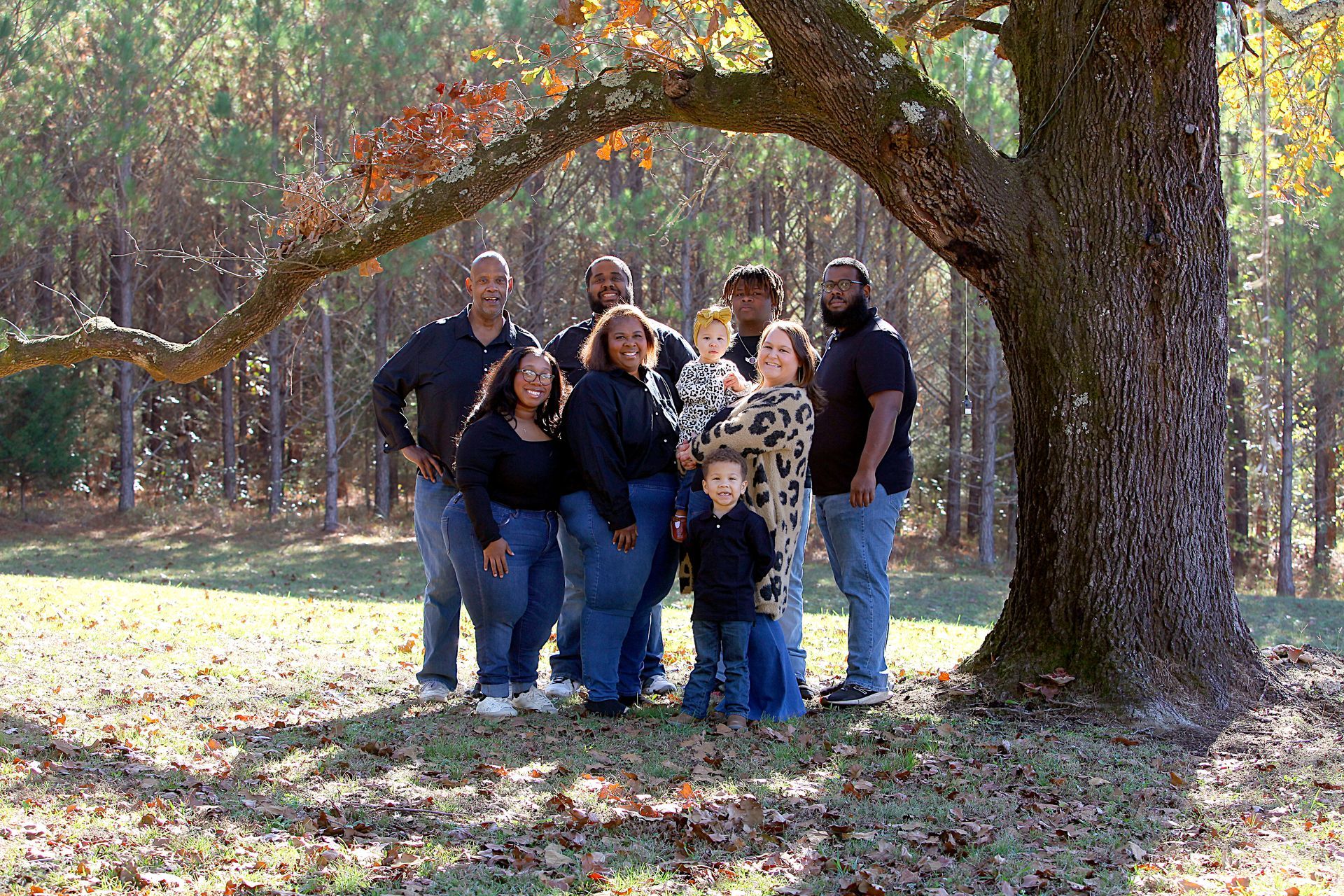A group of people standing under a tree in a park.