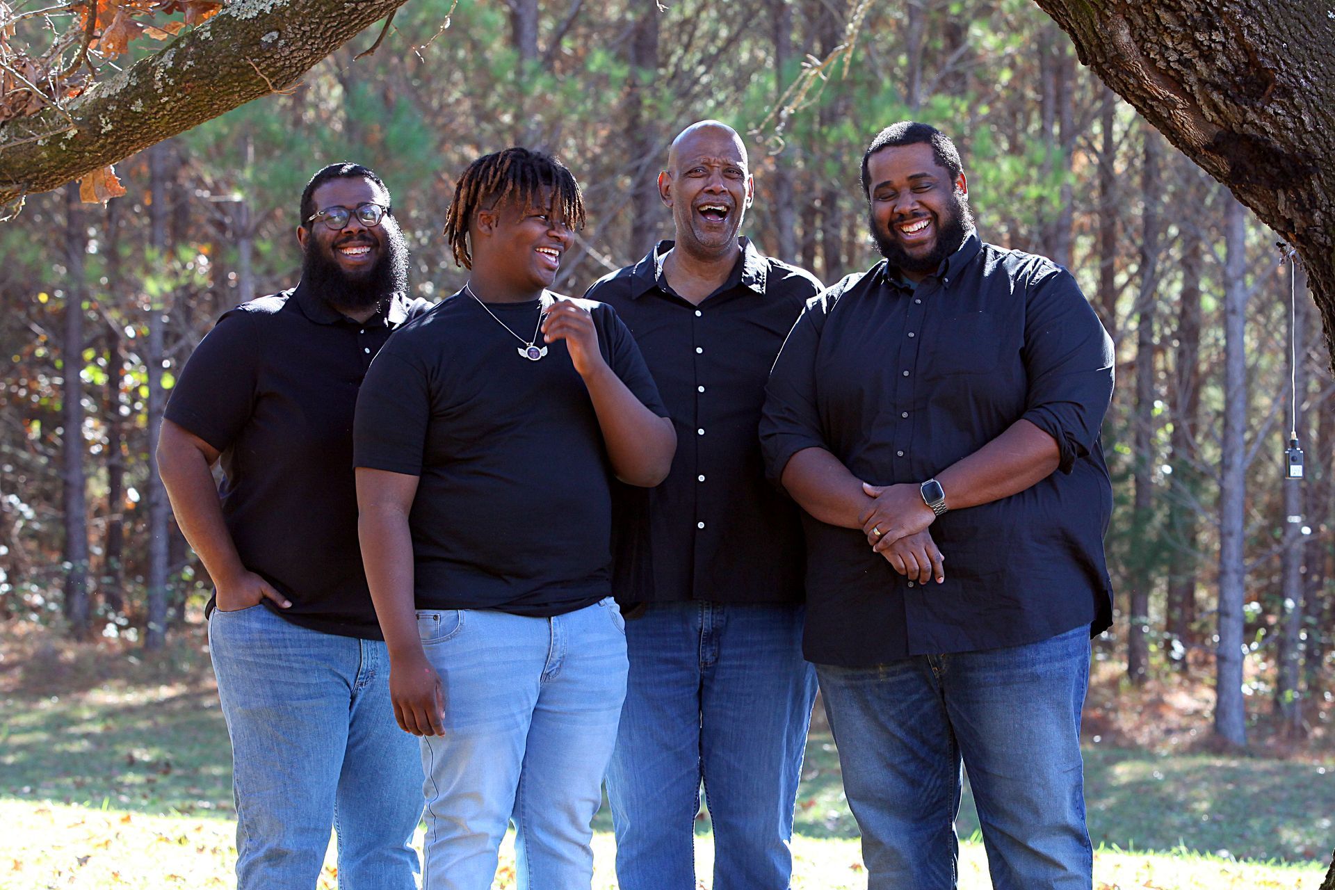 A group of men are posing for a picture in the woods.