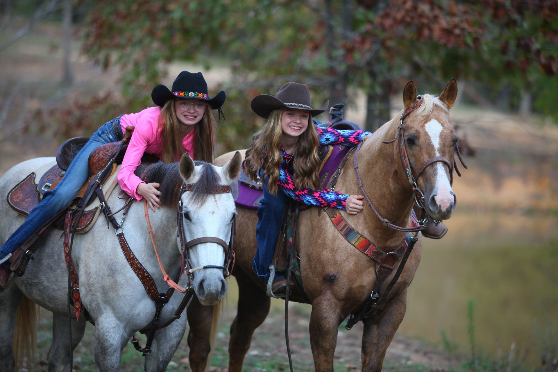 Two young girls are riding horses in a field.