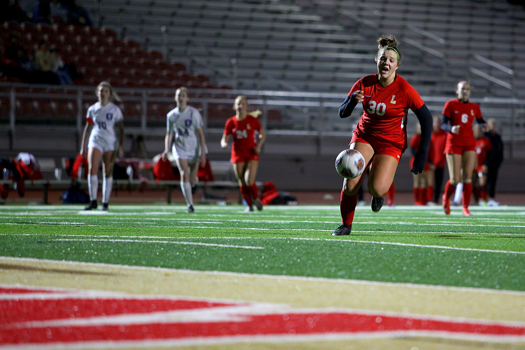 A woman is running with a soccer ball on a field.