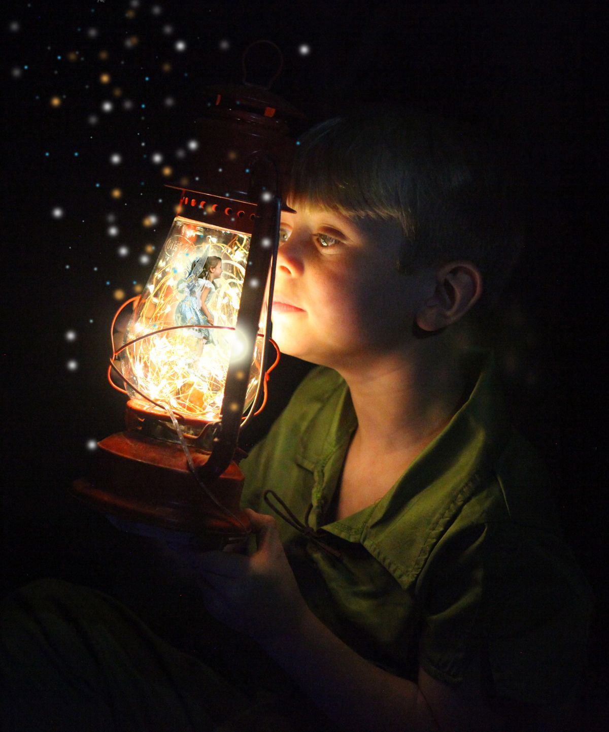 A young boy is holding a lantern with a picture of a fairy on it.