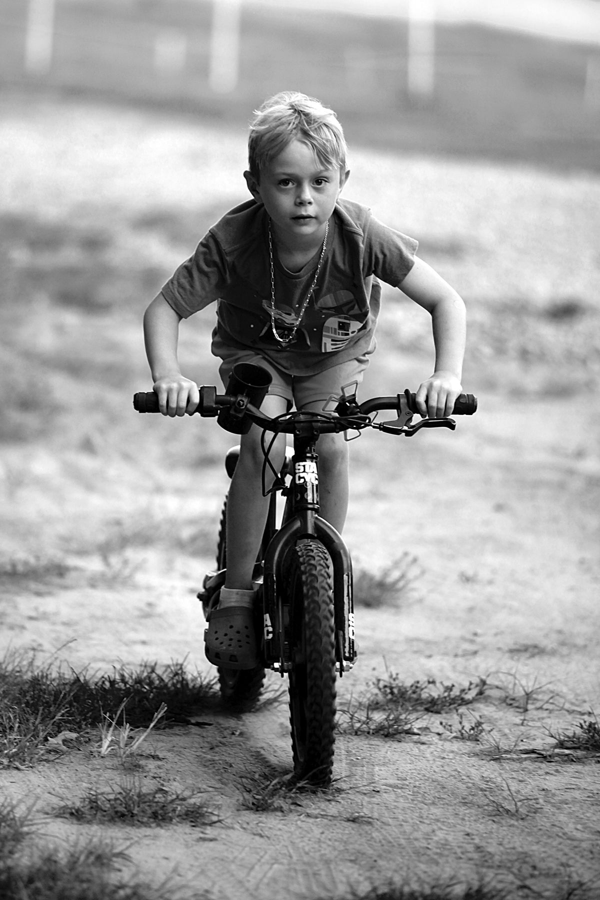 A young boy is riding a bike on a dirt road.
