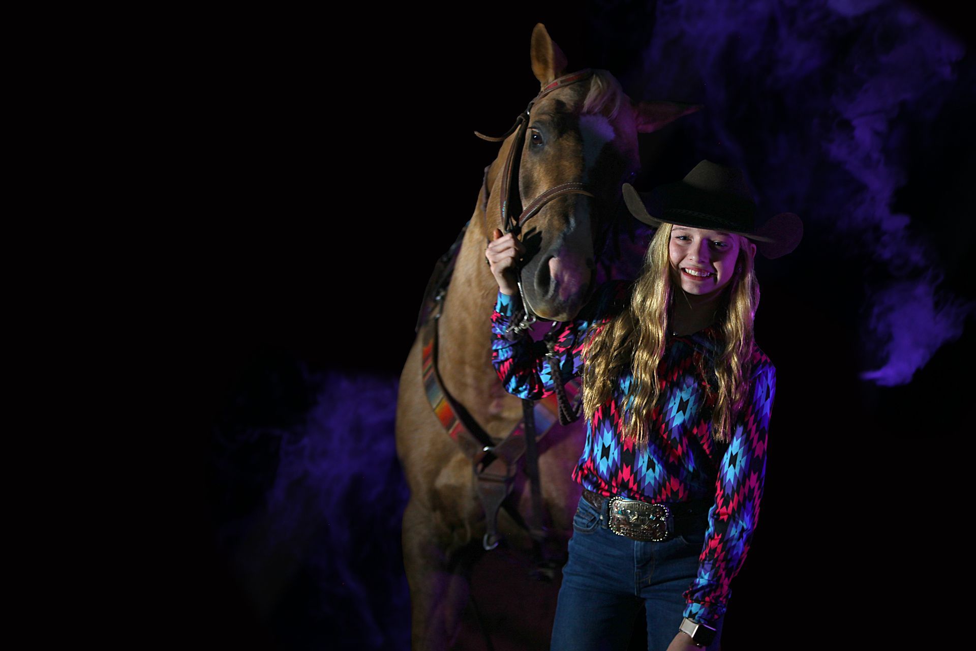 A little girl dressed as a fairy is sitting on a rock in the woods.
