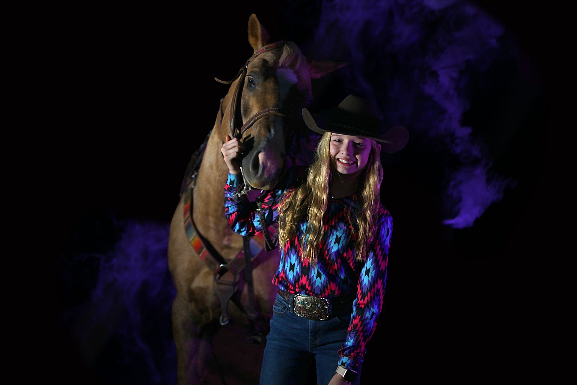 A woman in a cowboy hat is standing next to a horse.