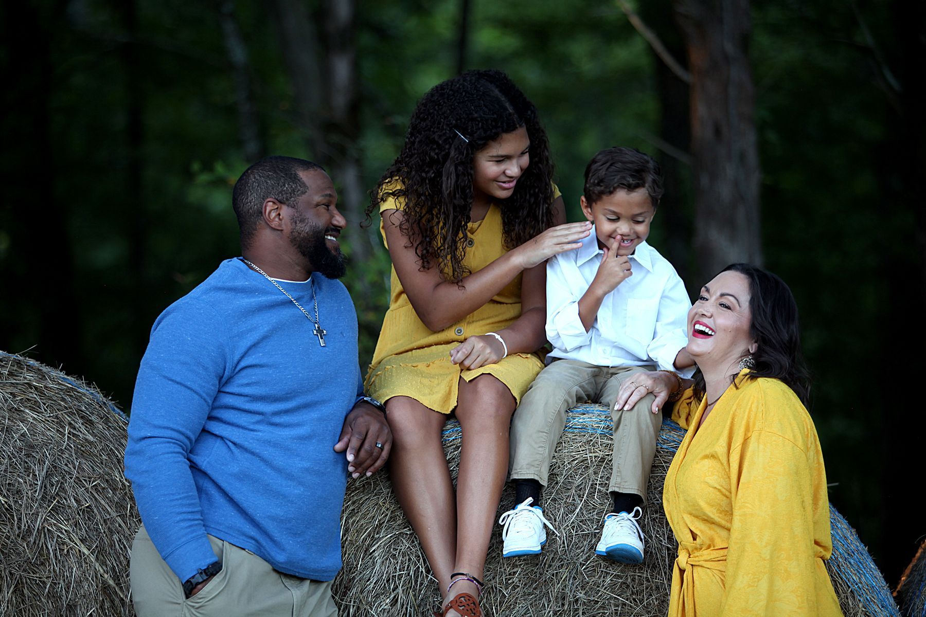 A family is sitting on a rock together and laughing.
