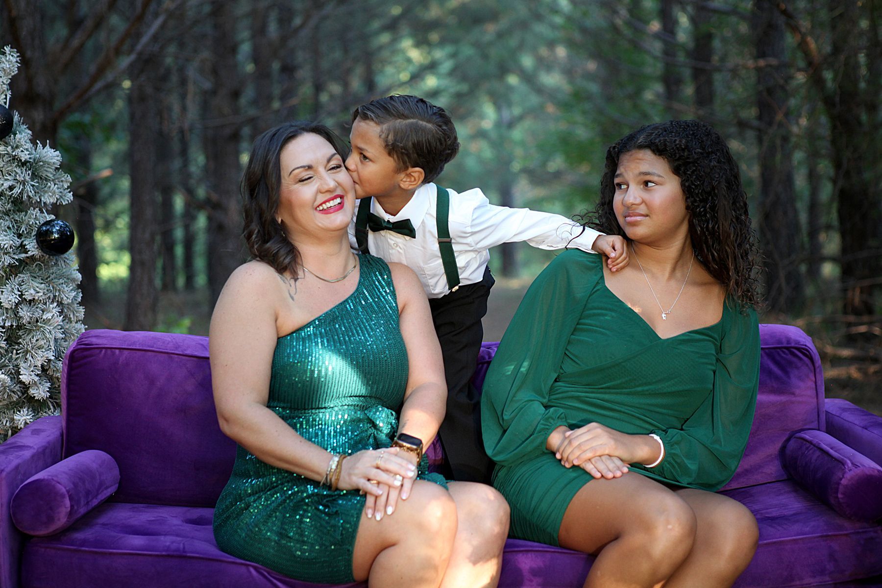 A woman and two children are sitting on a purple couch.
