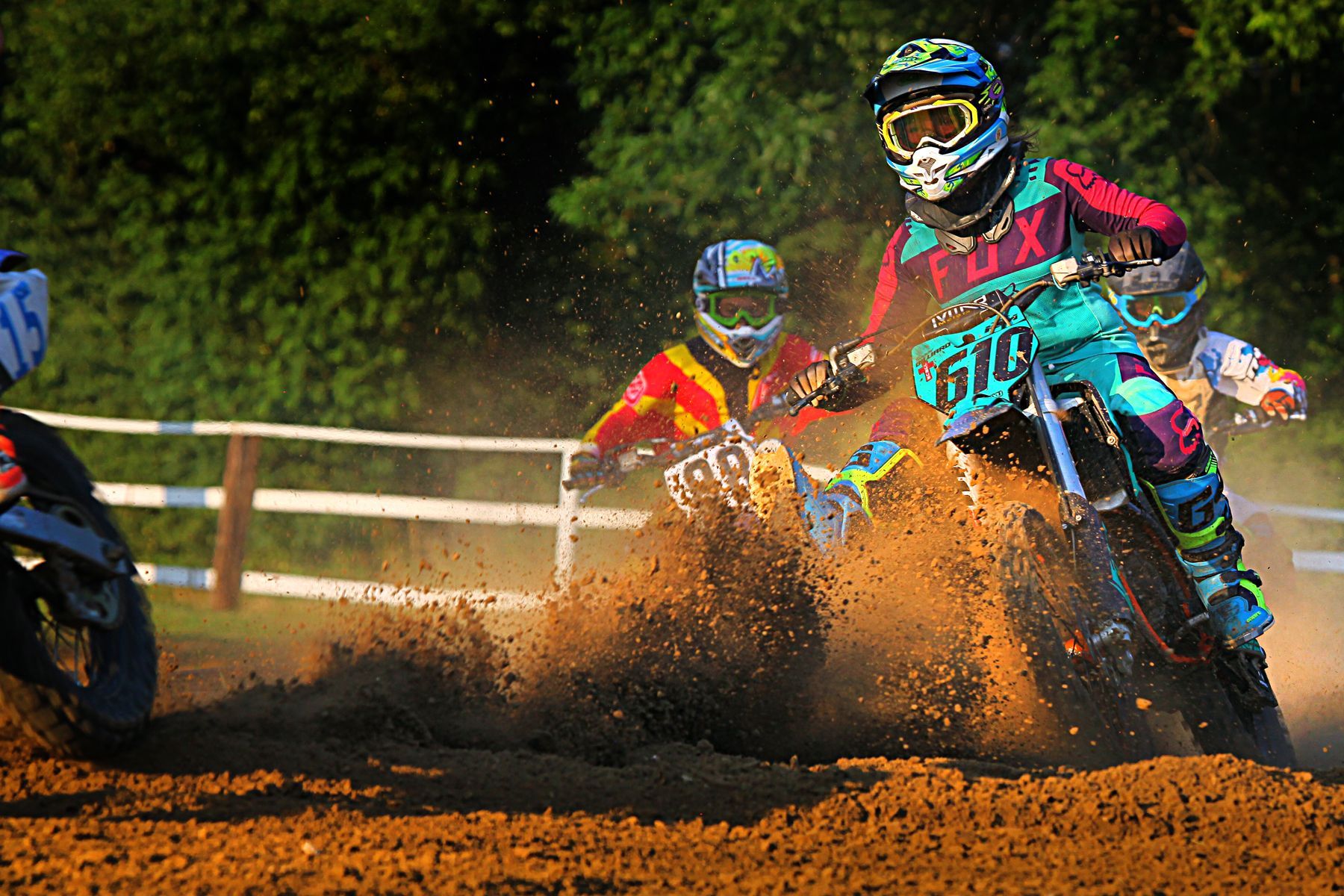 A group of dirt bike riders are racing on a dirt track.
