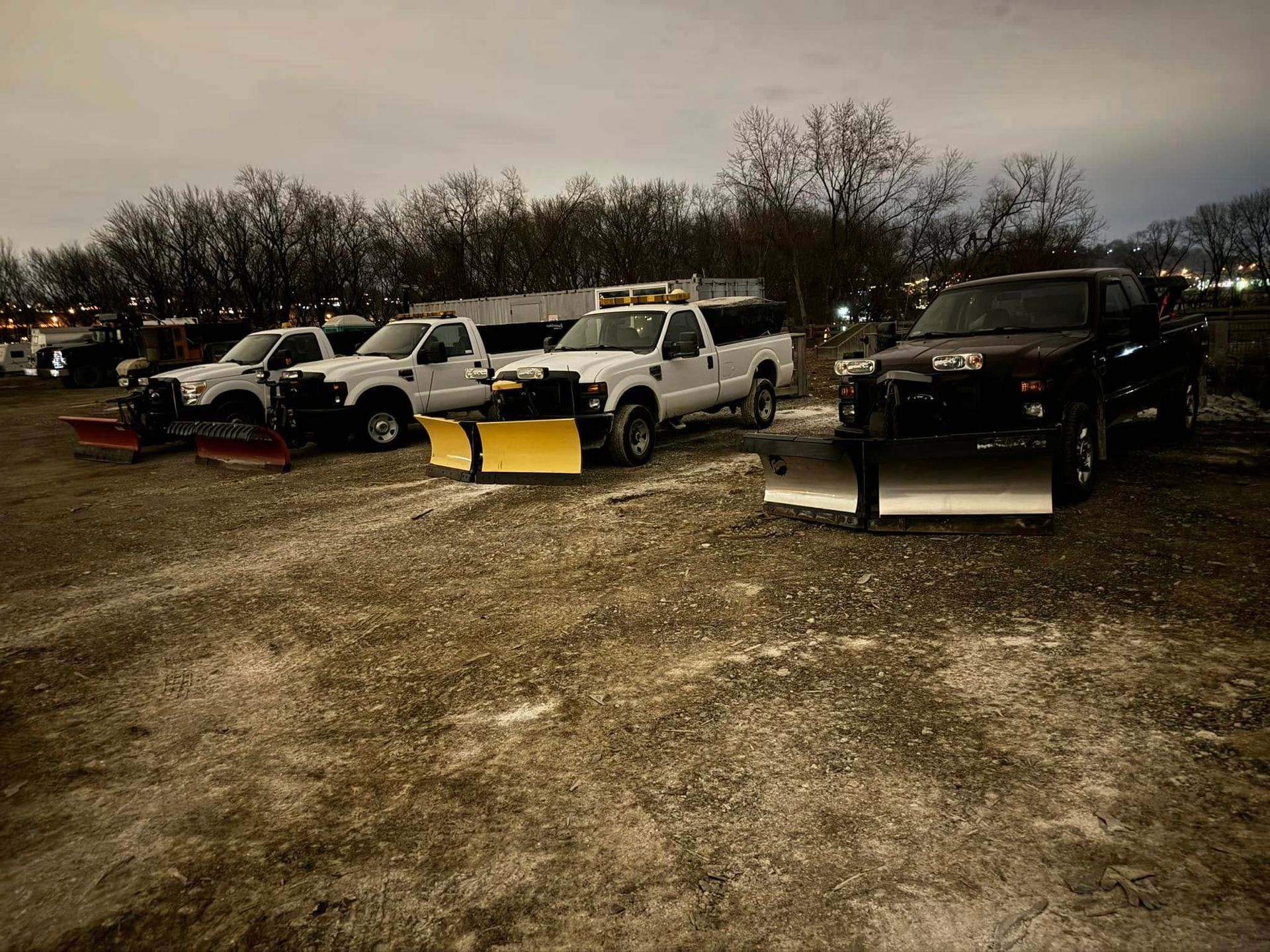 Snowplow trucks parked outdoors, awaiting a storm.