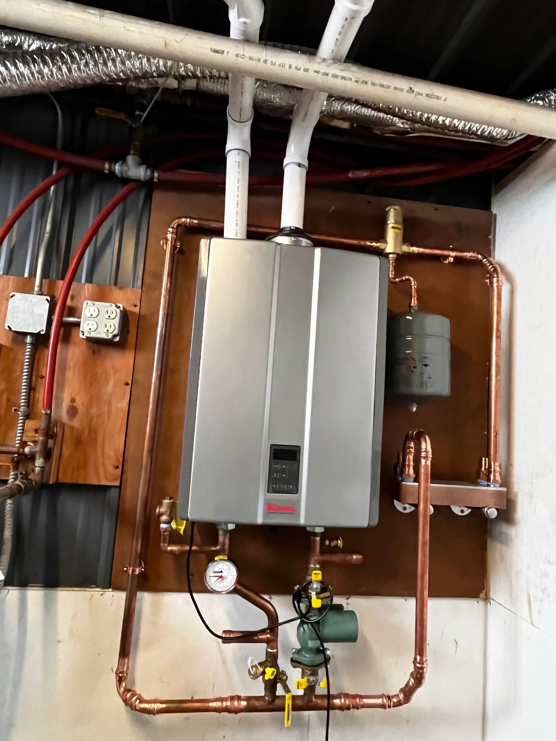 A water heater is hanging from the ceiling in a basement.