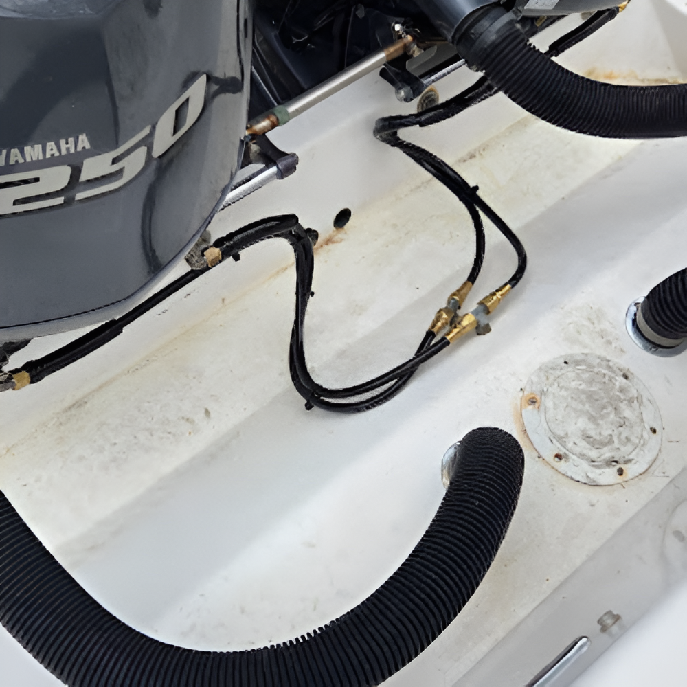 Close-up of a white boat's engine compartment with a Yamaha 250 engine. Black hoses and tubes are visible.