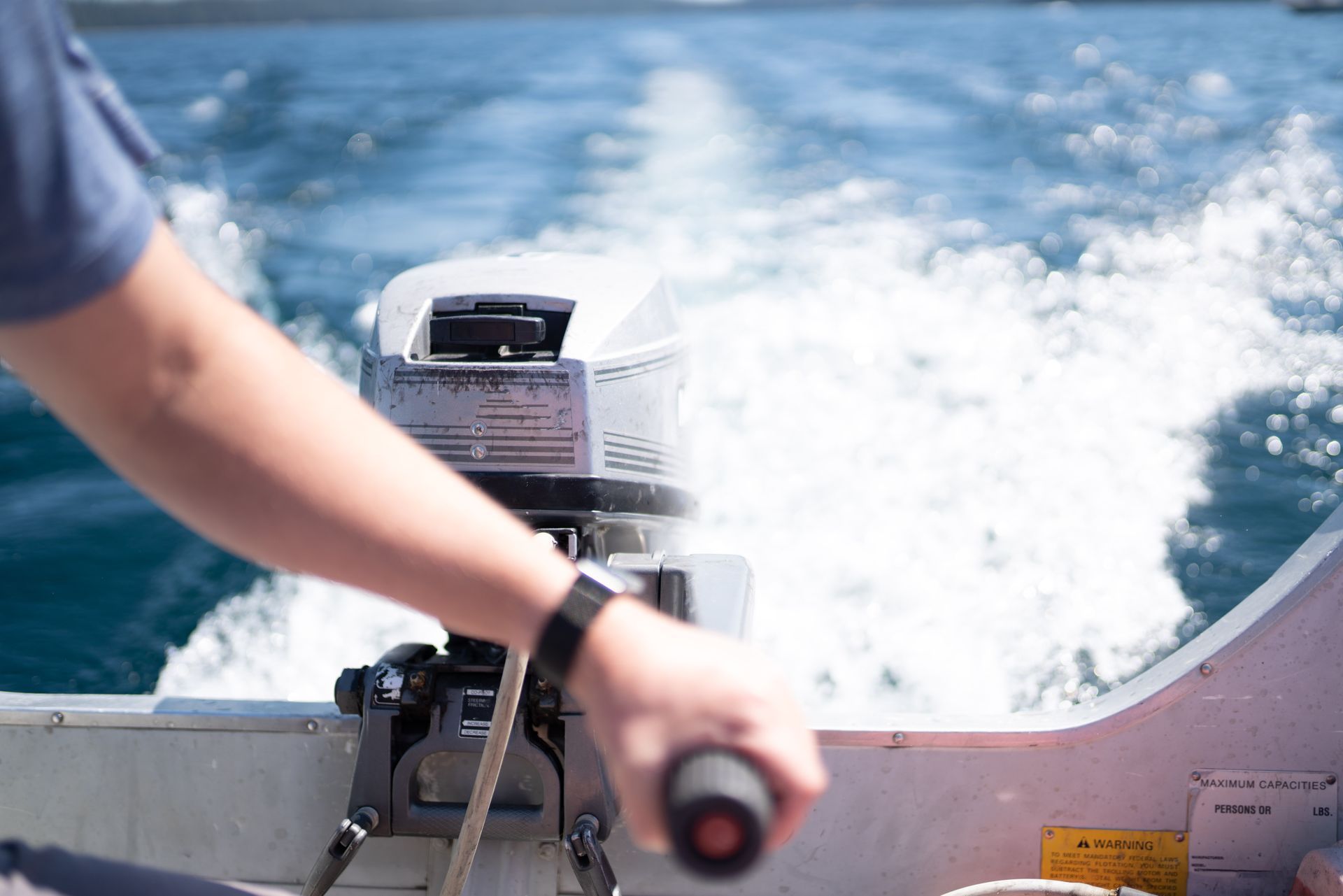Black engine with a belt and pulley visible against a blue sky with a flag in the background.