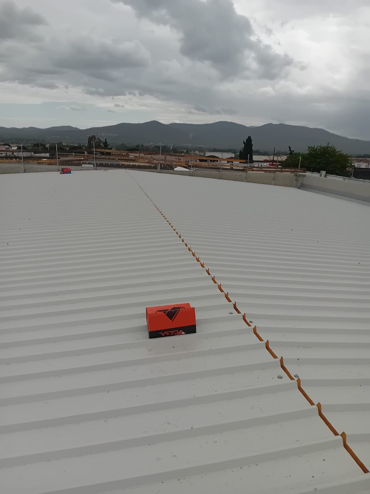 Una scatola rossa è seduta sopra un tetto bianco.