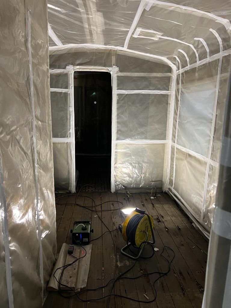 Una stanza con la plastica che ricopre le pareti e un ventilatore sul pavimento.