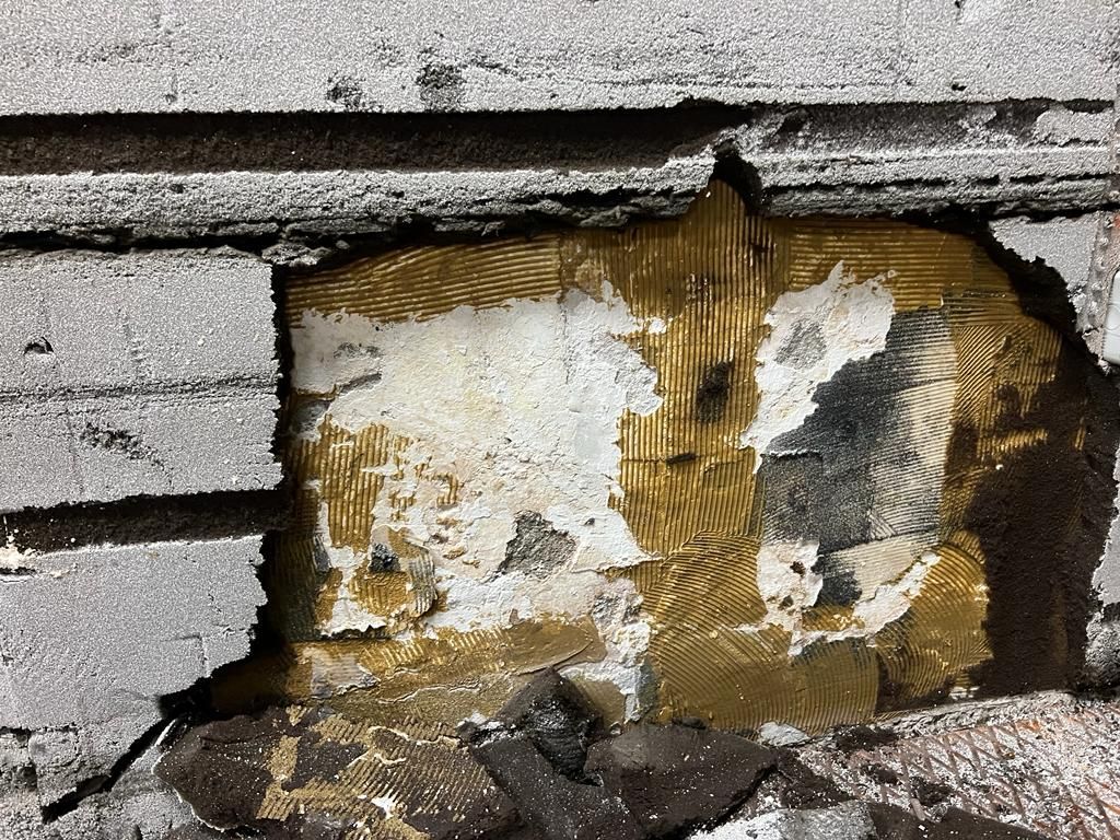 Un primo piano di un muro di mattoni con un buco.