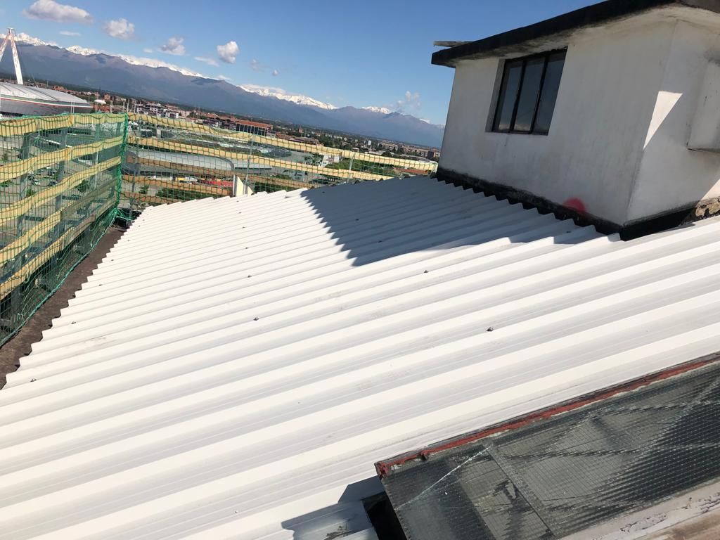 Un tetto bianco con una finestra e le montagne sullo sfondo