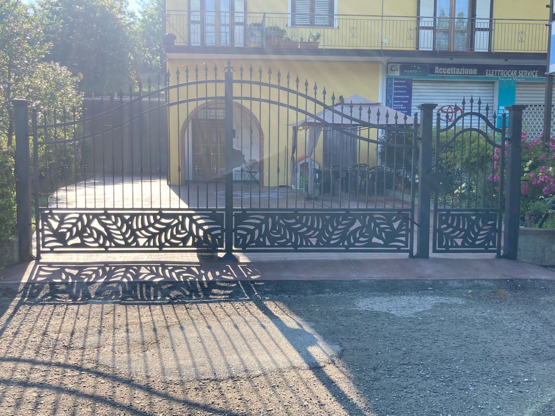 Cancelli in metallo nero decorato di fronte a un edificio giallo con un ingresso ad arco.