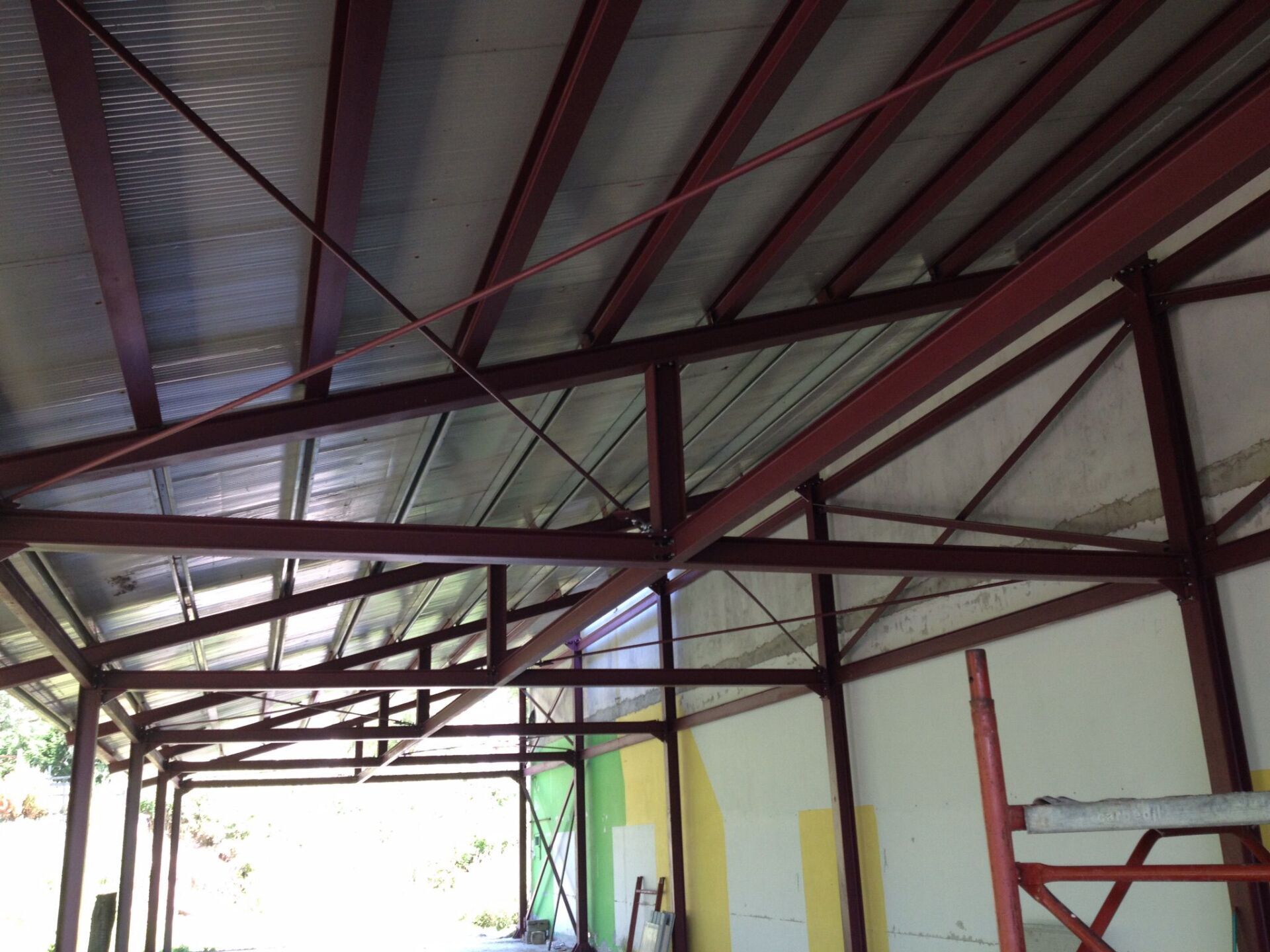 Struttura in acciaio rosso dell'interno di un edificio con supporti del tetto e isolamento riflettente.