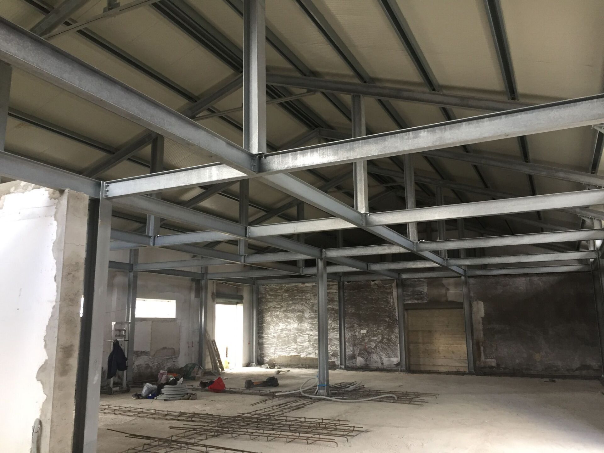 Interno di un edificio in costruzione, tetto e pareti con struttura metallica, spazio aperto, non finito.