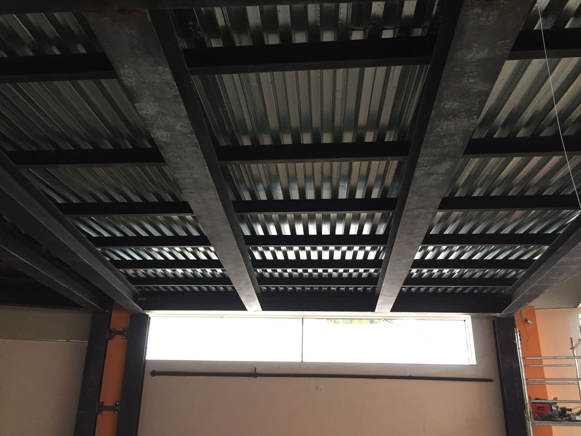 Travi in ​​acciaio e lamiera ondulata che formano la struttura del soffitto sopra una finestra e le pareti interne.