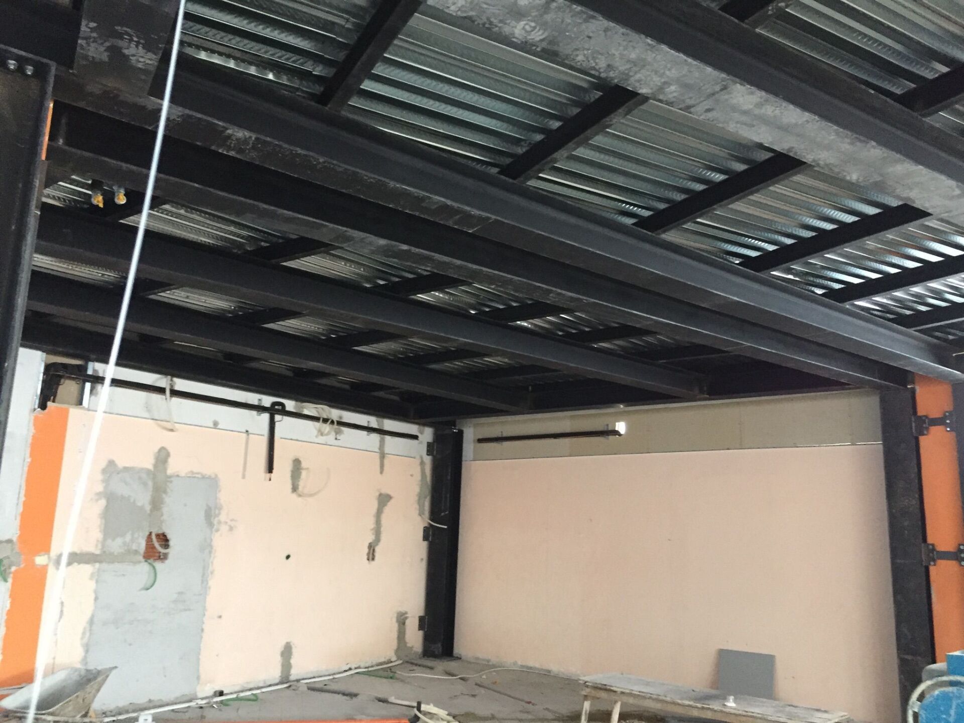 Travi in ​​acciaio e lamiera ondulata formano la struttura del soffitto di una stanza non finita.