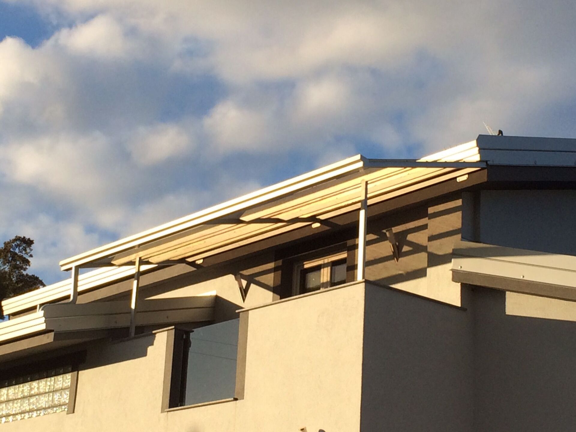 Esterno di un edificio moderno con un balcone ombreggiato sotto un cielo luminoso.