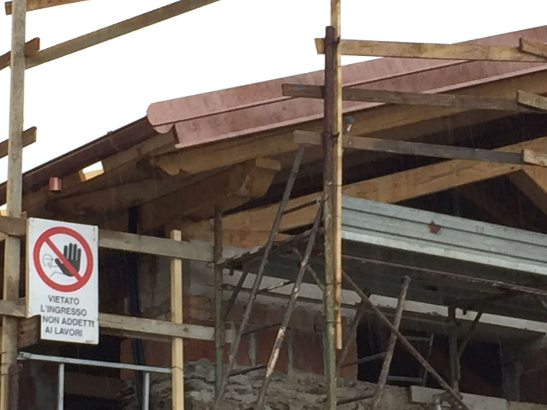 Cantiere con impalcature e tetto nuovo. Cartello: 