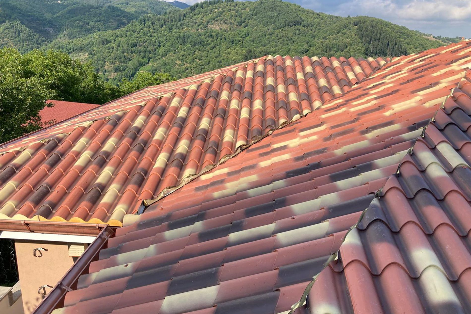 Tetto di tegole multicolori con montagne sullo sfondo.