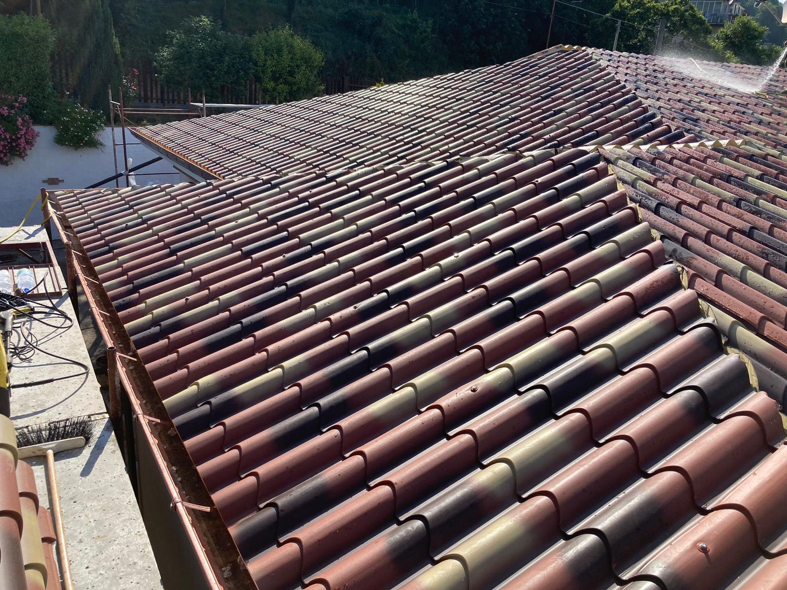 Tetto in tegole di argilla pulito con getto d'acqua.