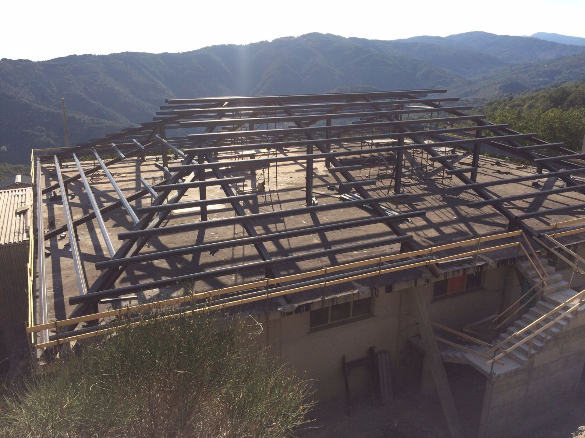 Tetto carbonizzato di un edificio, con travi a vista e una catena montuosa sullo sfondo.