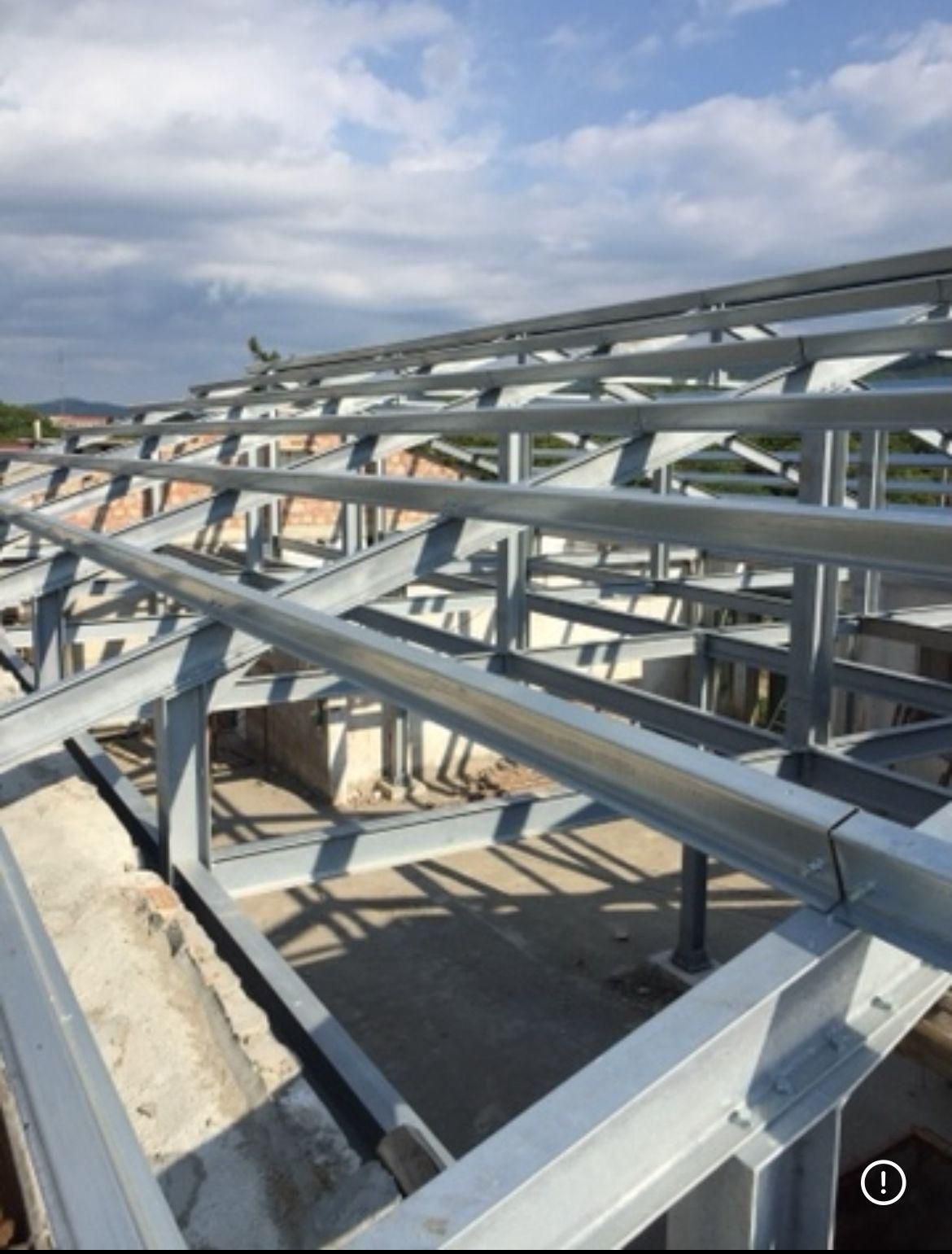 Interno di un magazzino vuoto con pavimento in cemento, travi metalliche e banchine di carico.