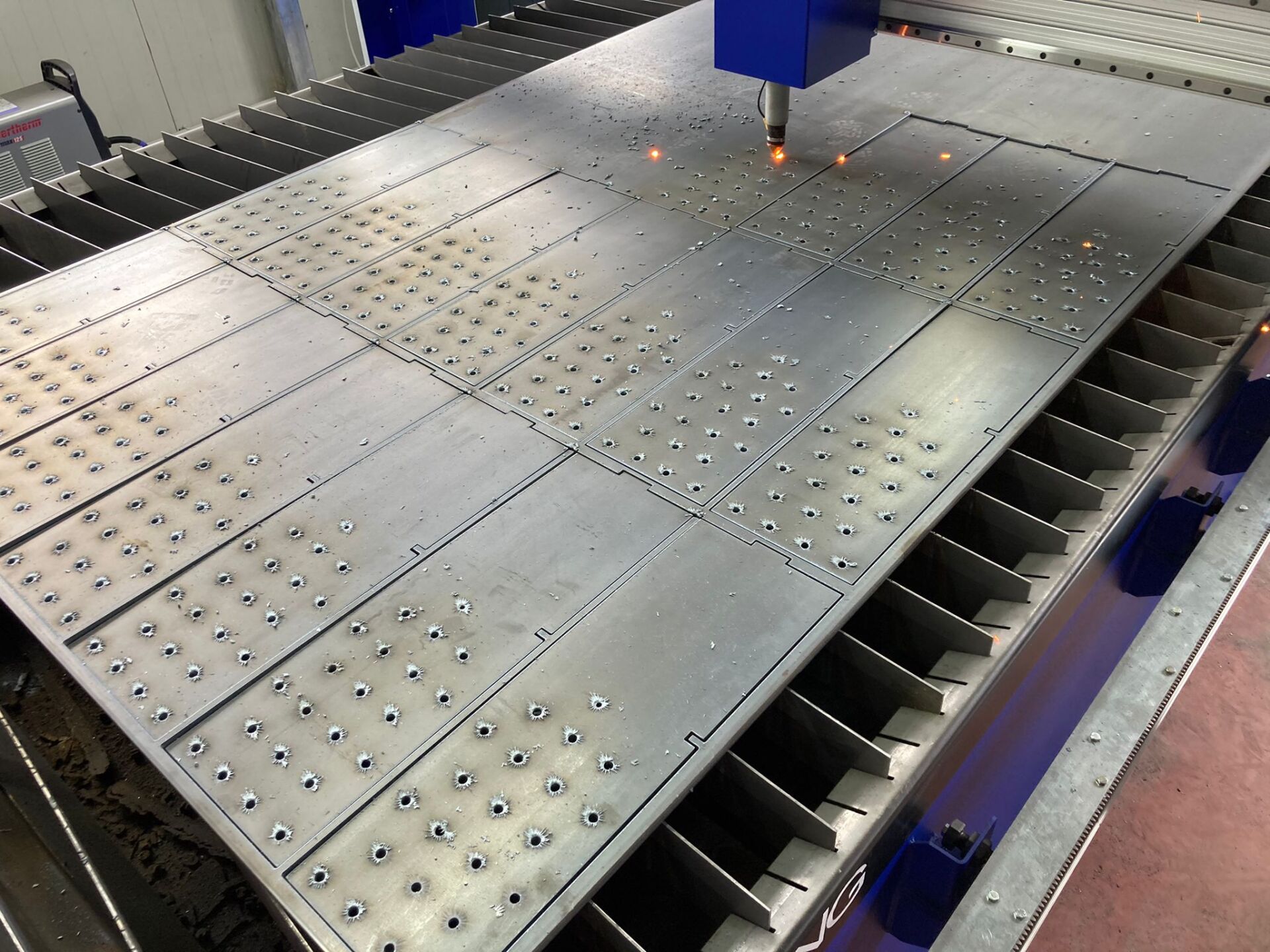 Taglierina laser in azione, taglio di lamiere; scintille visibili, ambiente industriale.